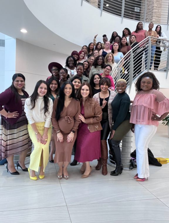 The women of EIB gathered on a spiral staircase at a leadership event