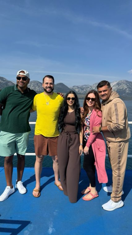 Five EIB teammates on a boat deck with mountains and open water behind them
